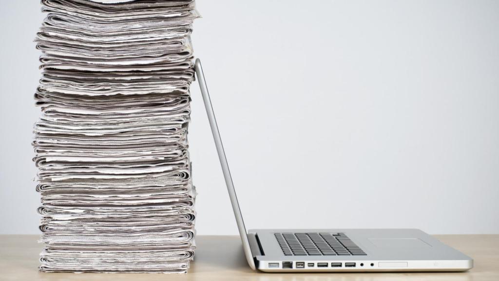 Una pila de periódicos sobre un ordenador portátil