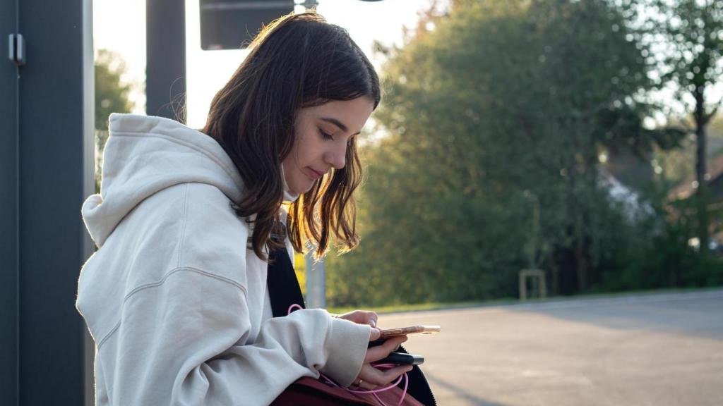 Joven esperando en una parada de autobús.