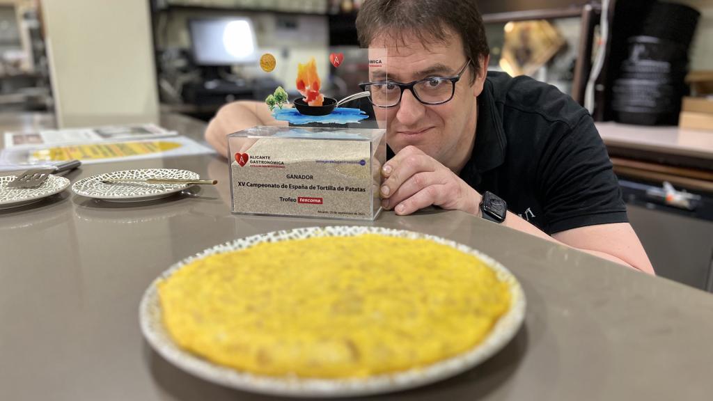 Carlos Olabuenaga posa junto a la mejor tortilla de patata de España y el trofeo que lo certifica