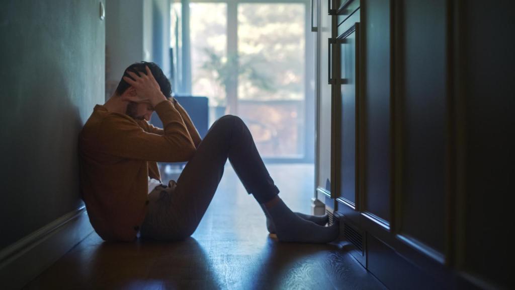 Un hombre sentado en el suelo con las manos en la cabeza