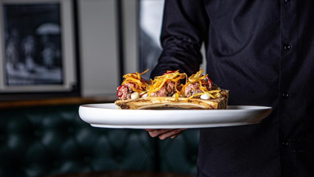 Un camarero sostiene un plato en su camino hacia una mesa, en imagen de archivo.