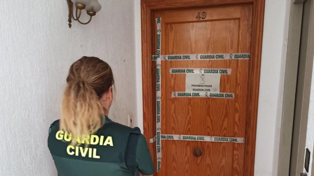 Una agente, en la puerta de entrada a la casa.