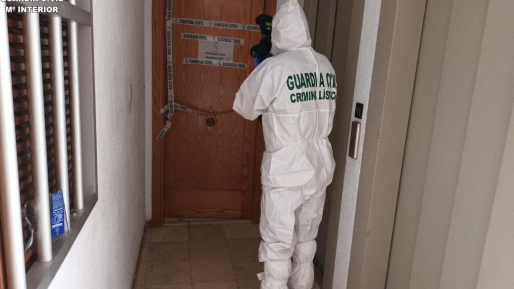 Un agente de la Guardia Civil recoge pistas del crimen ocurrido en un domicilio en Cullera.