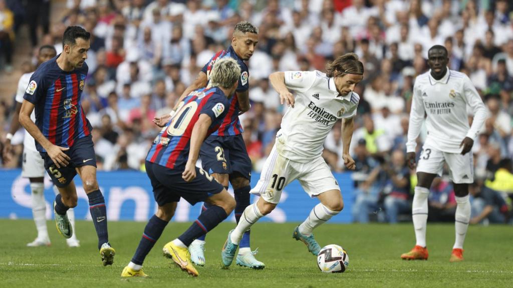 Luka Modric sale de la presión de varios jugadores del FC Barcelona