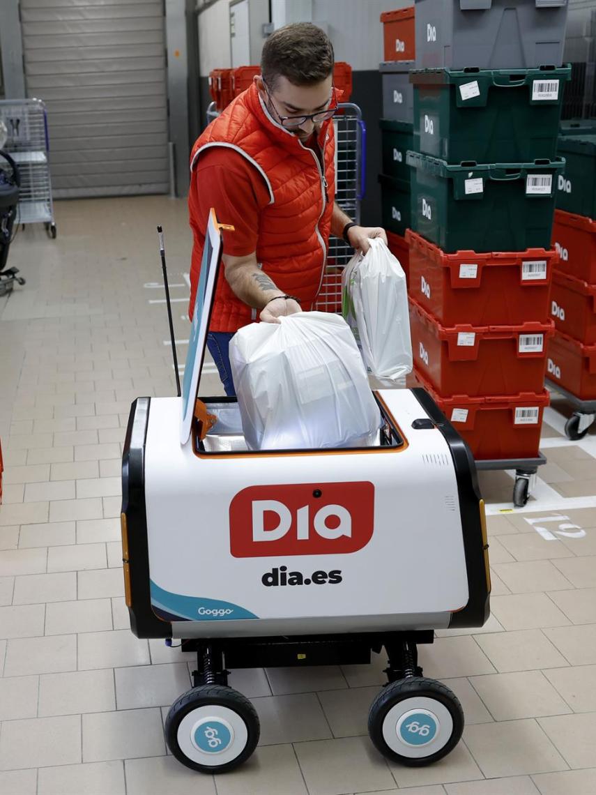 Un trabajador de Dia, depositando un pedido en un robot repartidor.