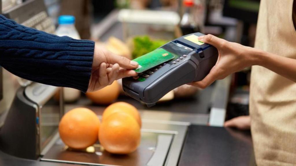 Un hombre pagando con tarjeta en un establecimiento.