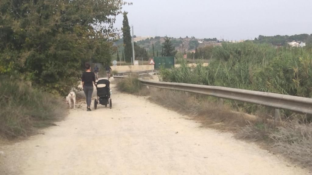 Una vecina y un par de ciclistas, este lunes, por la mota del río Segura en la pedanía murciana de Javalí Nuevo.