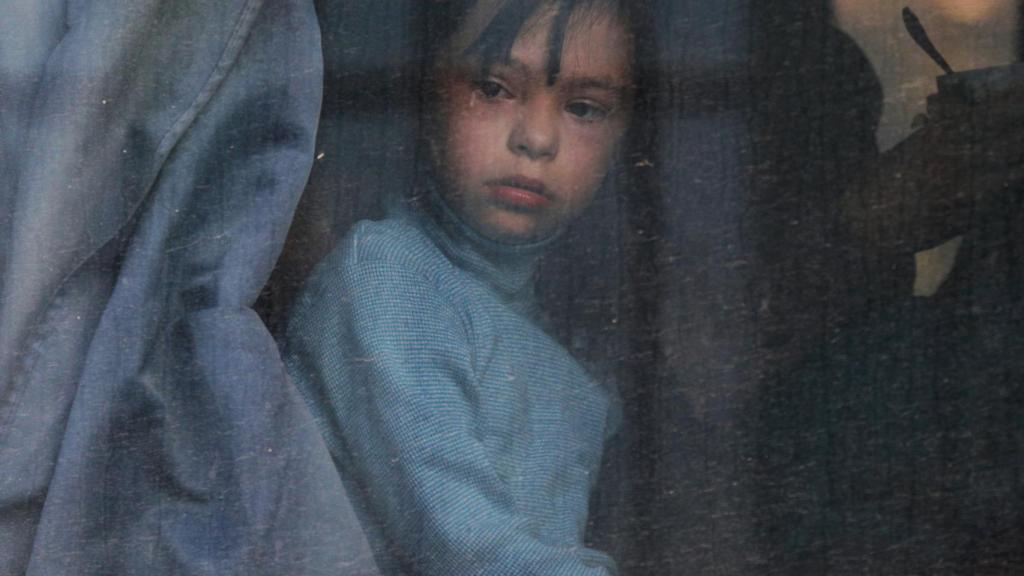 Un niño mira por la ventana de un autobús de deportados de Jersón.