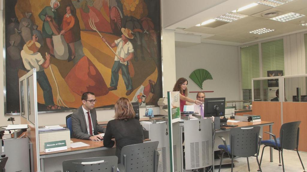 Empleados de una sucursal de Unicaja atendiendo a sus clientes