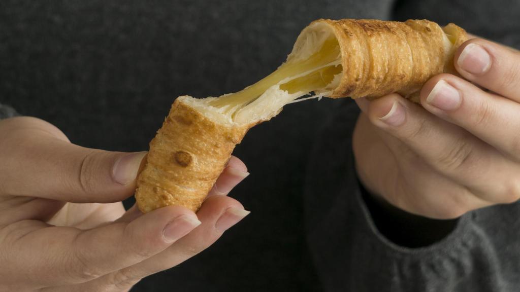 Una mujer sostiene un tequeño entre sus manos.