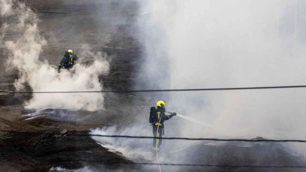 Dos bomberos trabajan en la extinción del fuego de la antigua fábrica de Pontesa dos días después de iniciarse el incendio.