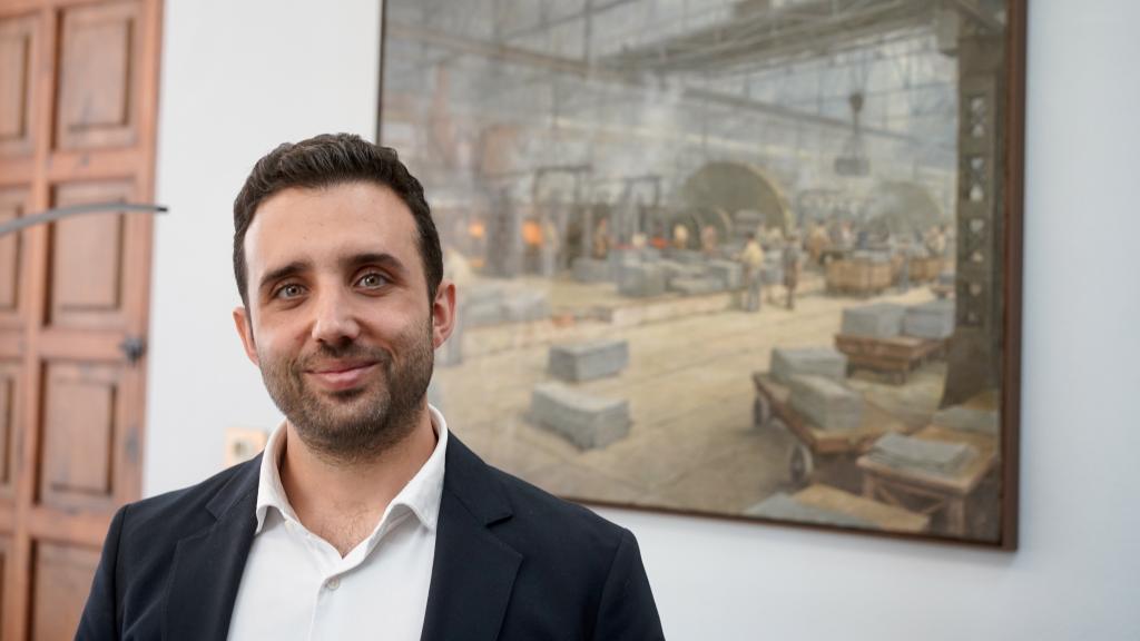 Darío Moreno posa en su despacho junto a un cuadro sobre la histórica industria siderúrgica de Sagunto.