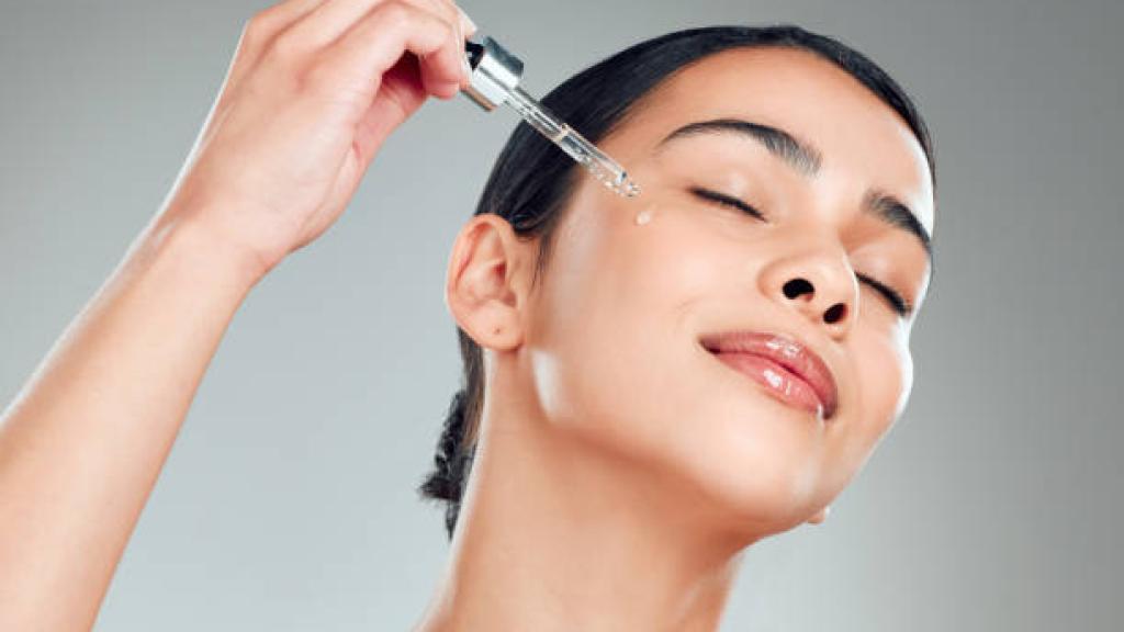 Mujer aplicándose sérum. Istock
