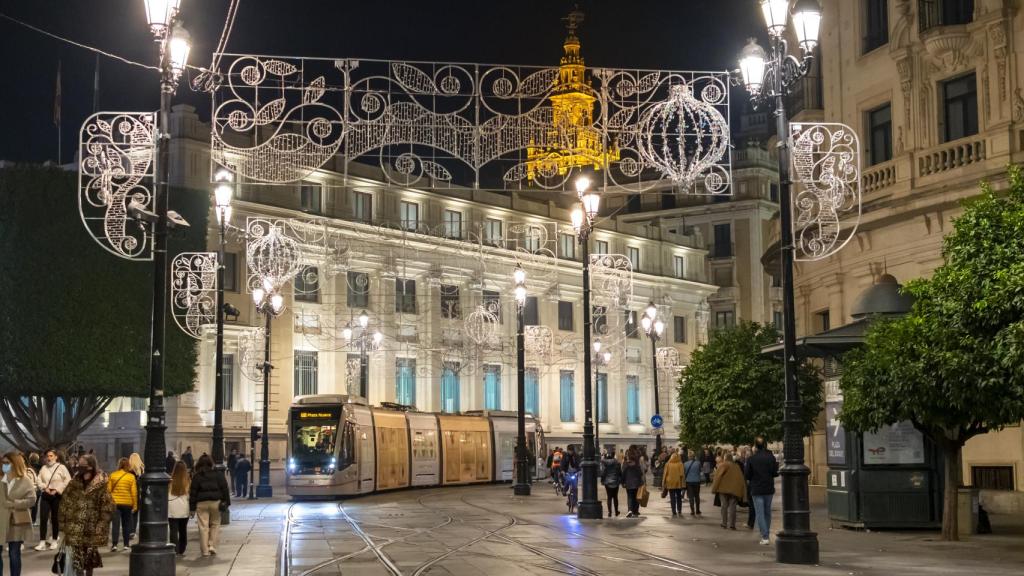 Decoraciones navideñas con la Torre de la Giralda de la Catedral de Sevilla iluminada detrás