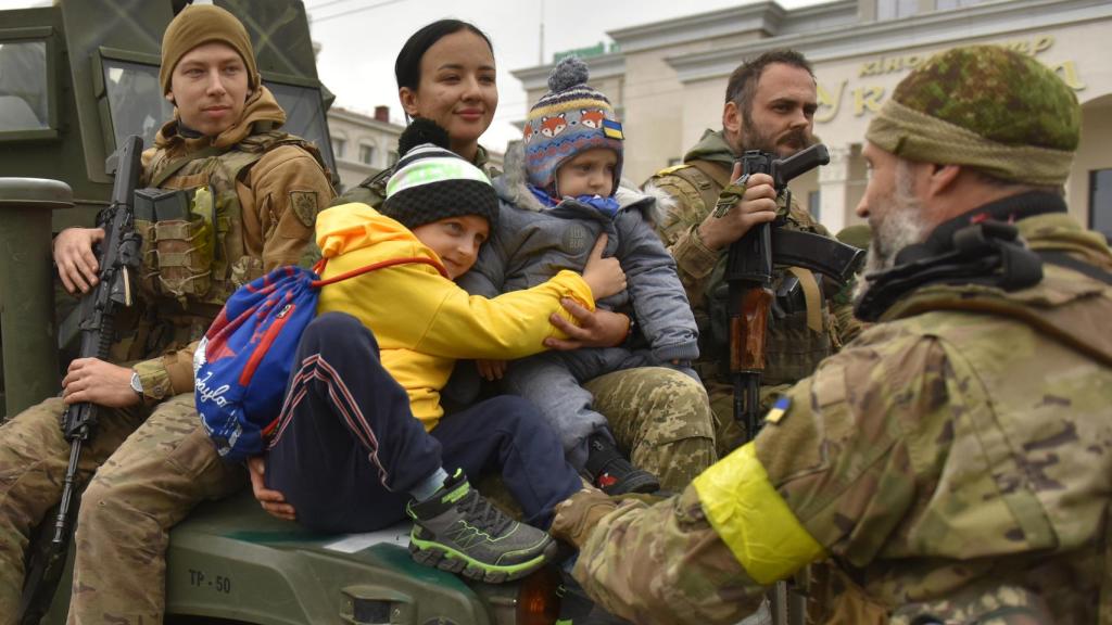 Una militar ucraniana abraza a unos niños en la plaza central de Jersón, en Ucrania.