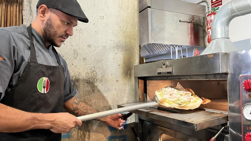 Un empleado mete una de las pinsas al horno.