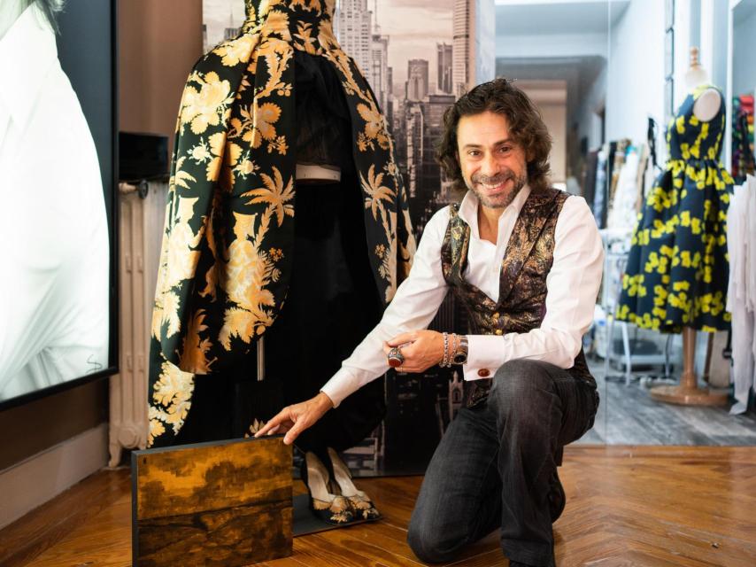 El creador, junto a uno de sus vestidos y uno de sus cuadros.