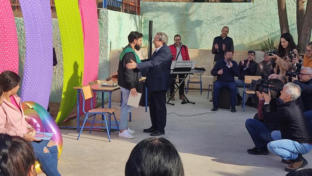 El rector de la universidad, José Ángel Narváez, colocándole la beca a José Francisco.