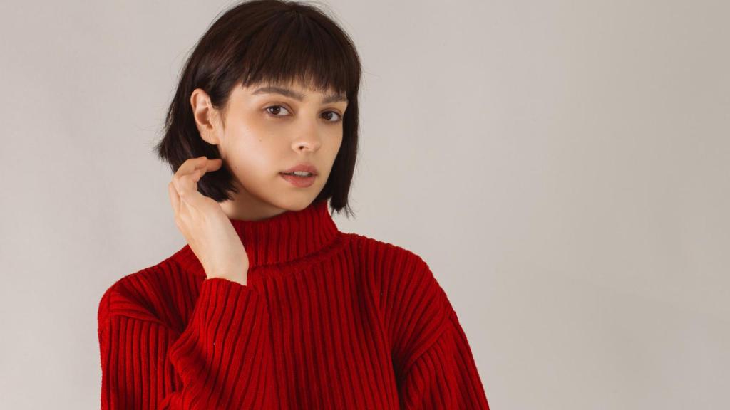 Una mujer con un jersey de cuello vuelto rojo.