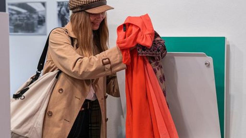 Una mujer deposita ropa en un contenedor para esta iniciativa.