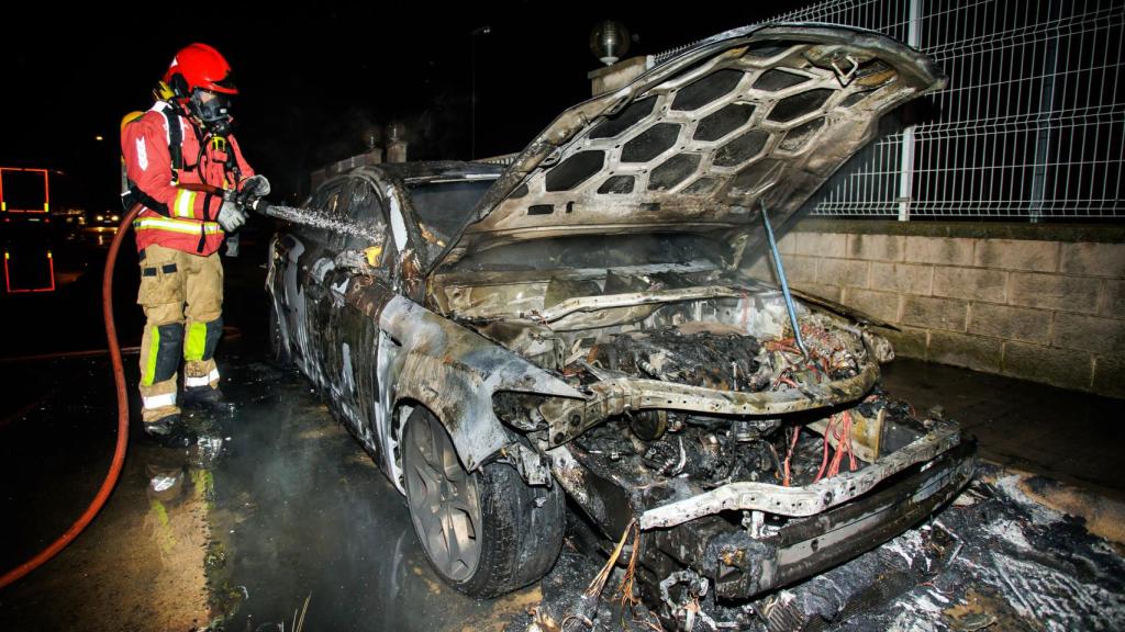 Los bomberos sofocando el vehículo calcinado
