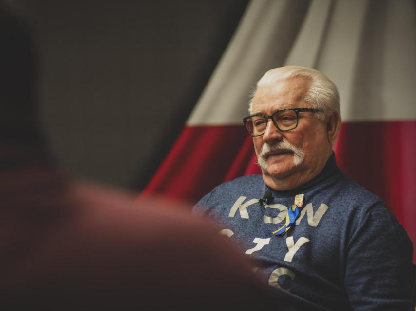 Lech Walesa, con una leve sonrisa y la bandera polaca a su espalda.
