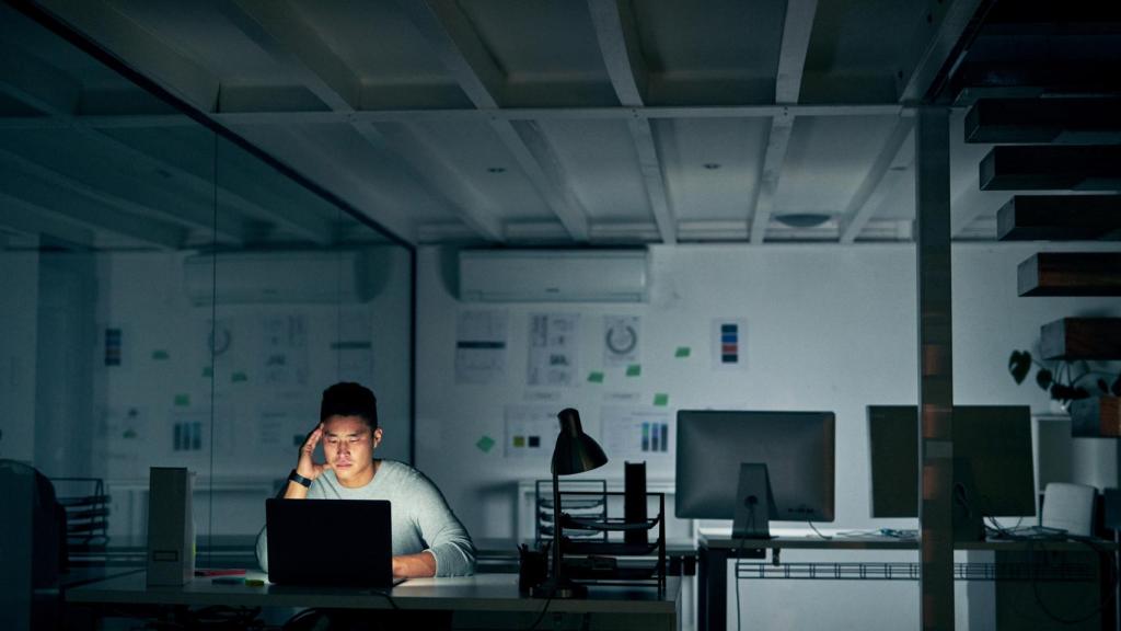 Imagen de archivo de una persona fatigada sola en una oficina.