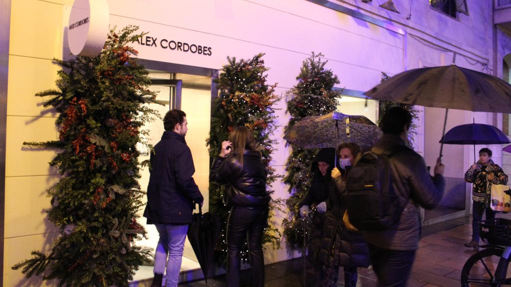 Varios clientes accediendo a la tienda de tartas de queso de Álex Cordobés pese a la lluvia.