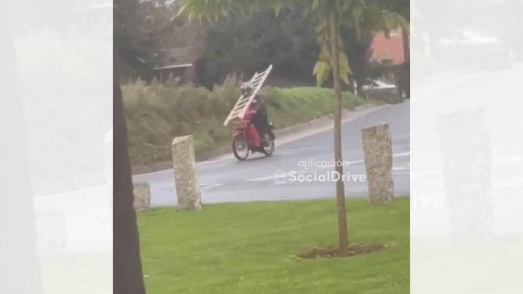 Motorista circulando por las calles de Ordes (A Coruña) con una escalera.