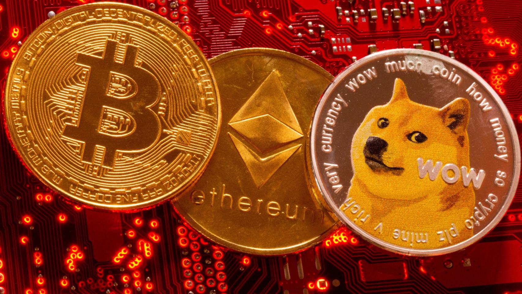 Representación de las criptomonedas Bitcoin, Ethereum y DogeCoin sobra la placa base de un ordenador.