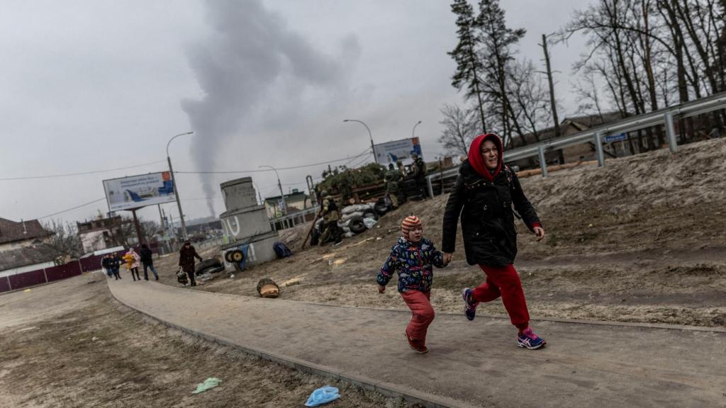 Los residentes locales corren para ponerse a cubierto en Irpin, después de fuertes bombardeos, en marzo de 2022.