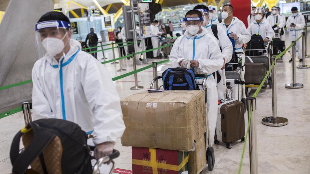 Trabajadores procedentes de China con trajes de protección en la terminal T4 del Aeropuerto Adolfo Suárez Madrid-Barajas, el 21 de mayo de 2021.