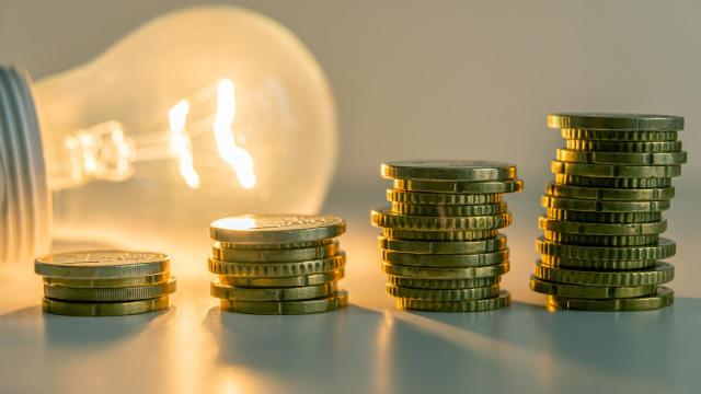 Una bombilla junto a varias monedas para ilustrar el precio de la luz.