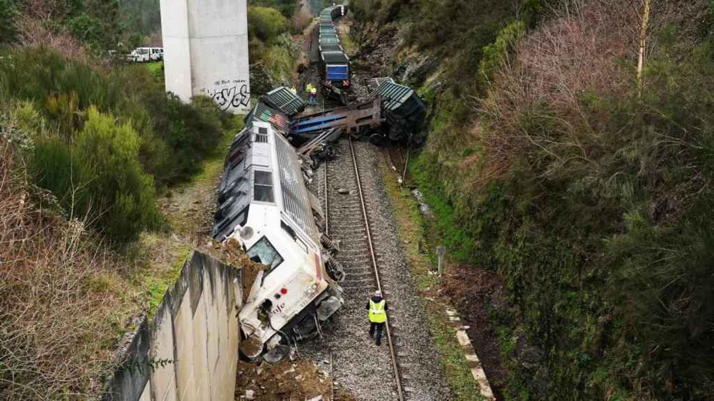 Dos hombres realizan las labores de retirada del tren accidentado en Lalín (Pontevedra).