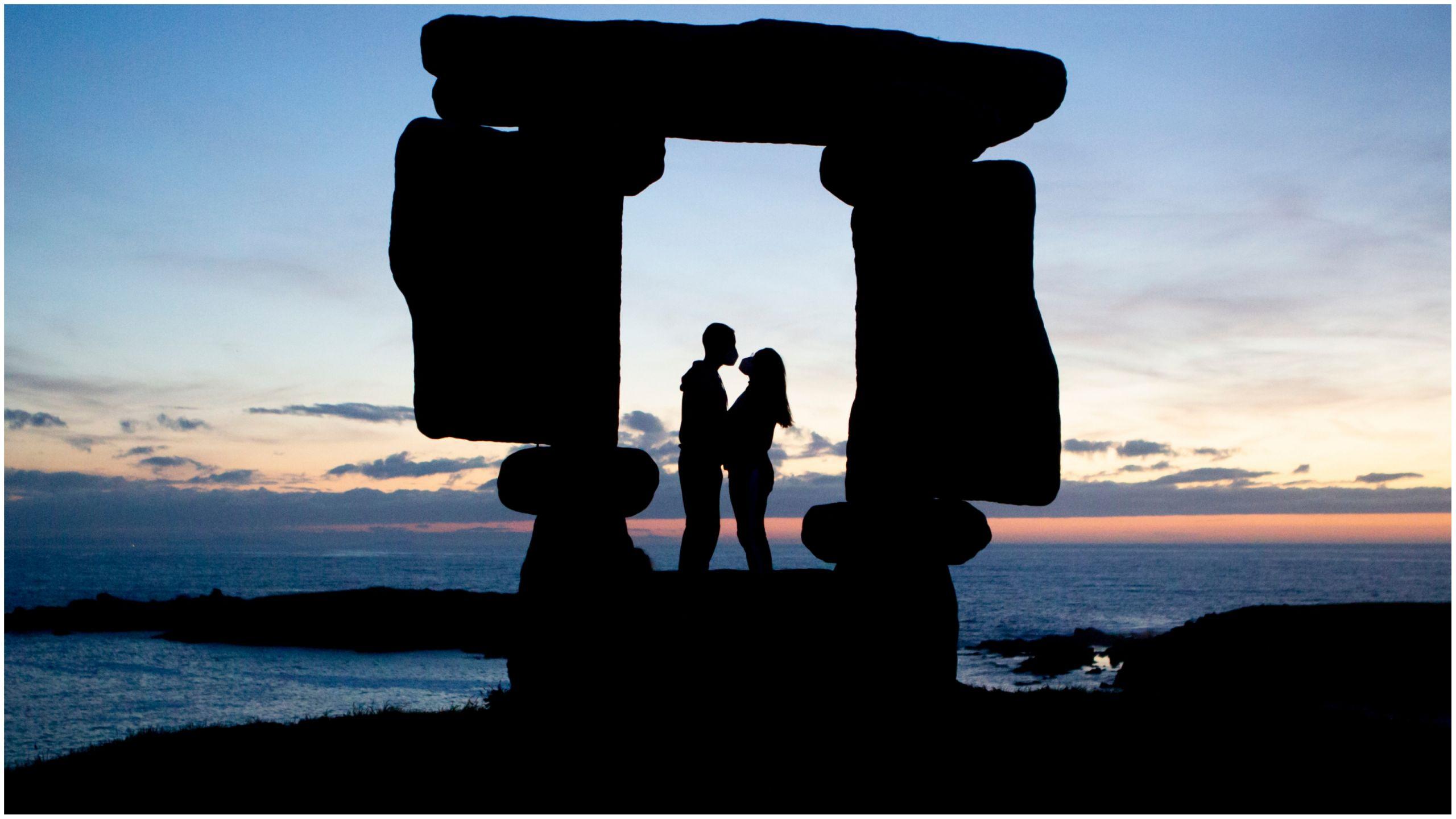 Pareja bajo la escultura de O Portiño. Foto: Shutterstock