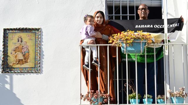 Munira (21) su hija Emma (2) y Rah (65), con la bandera saharaui, junto a un azulejo de la Virgen del Carmen.
