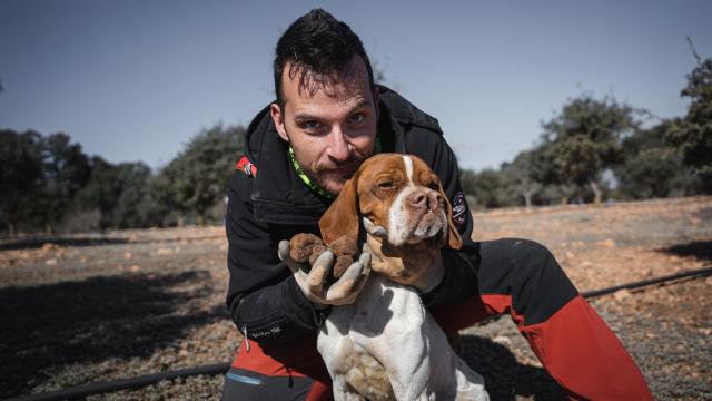 El truficultor Daniel Brito posa junto a Covid, su perro trufero, y cuatro trufas recién desenterradas.