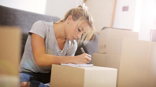 Una mujer en plena mudanza haciendo lista de cosas pendientes.