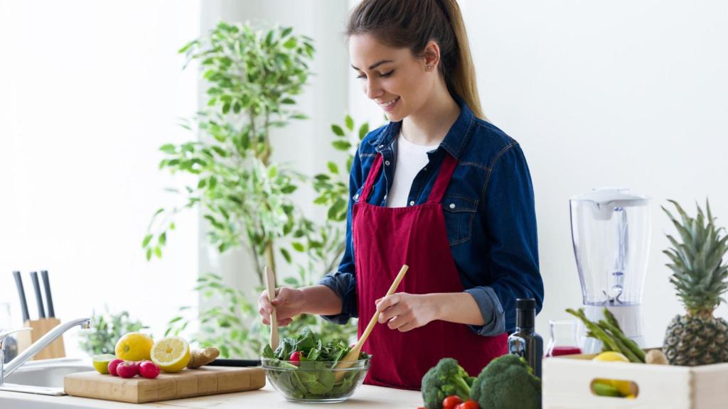 Mujer preparando una ensalada en la cocina.