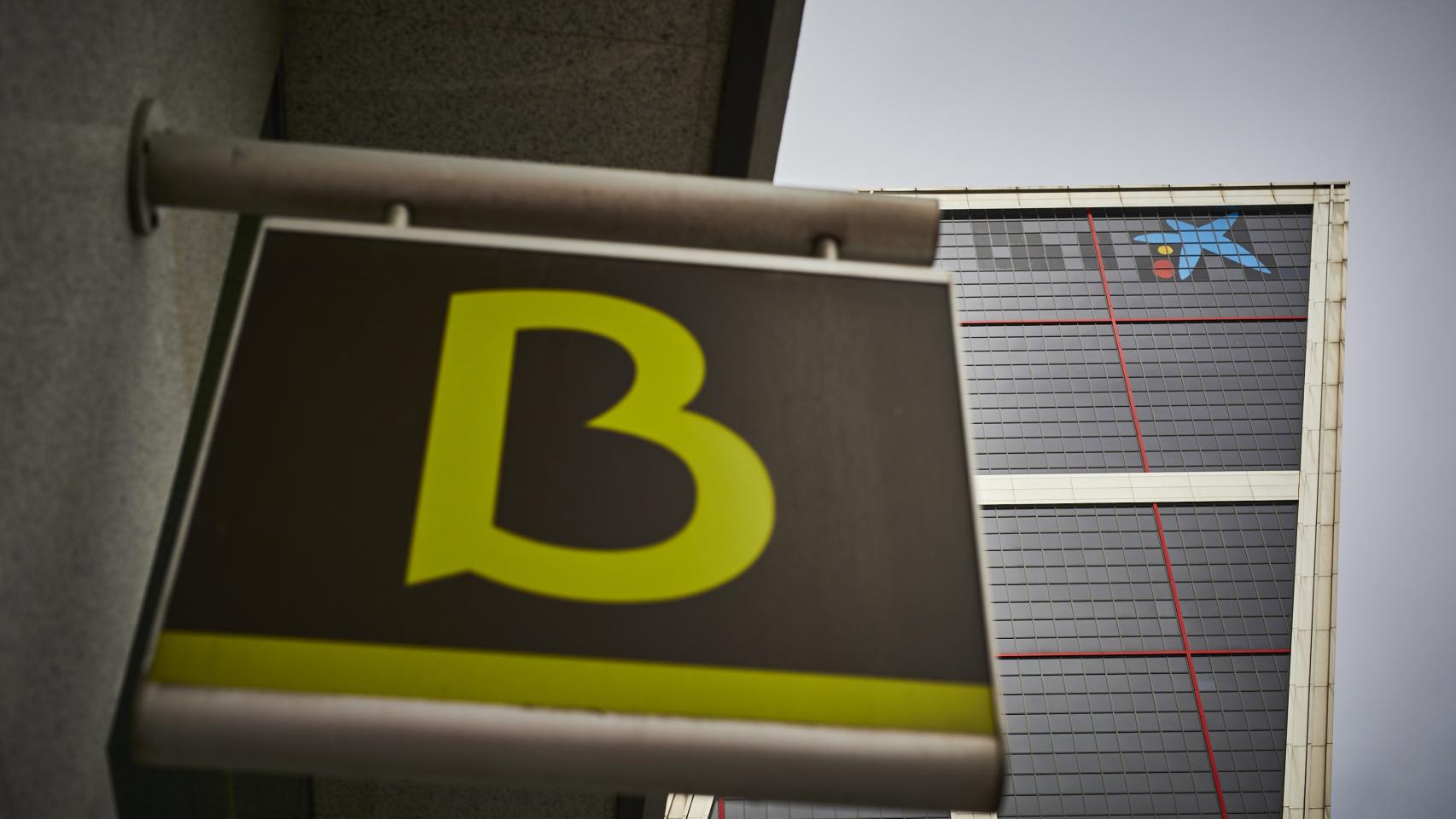 Un cartel con el símbolo de Bankia delante del logo de Caixabank tras su sustitución por el de Bankia en las torres Kio, en Madrid (España), en 2021.