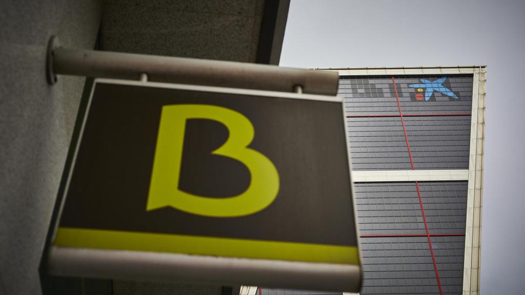 Un cartel con el símbolo de Bankia delante del logo de Caixabank tras su sustitución por el de Bankia en las torres Kio, en Madrid (España), en 2021.
