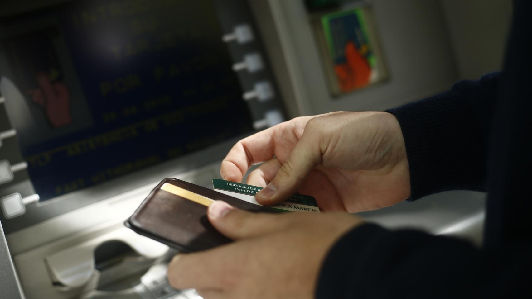Una persona utiliza un cajero automático con una tarjeta bancaria.