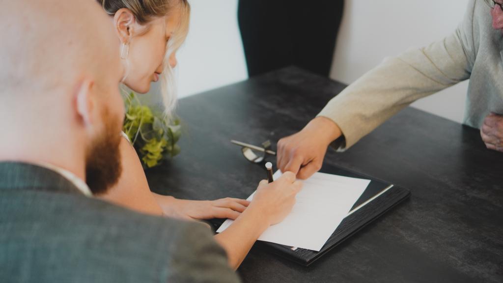 Pareja firmando documentos.