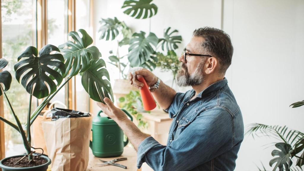 Un hombre rocía de agua las plantas de su casa.