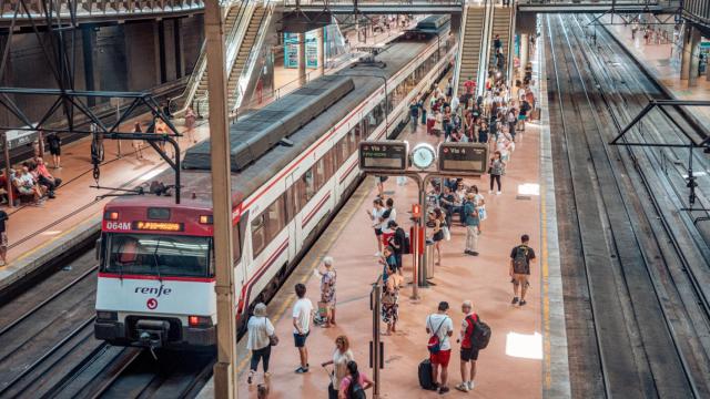 Varias personas en el andén de un tren de cercanías en la estación Almudena Grandes-Atocha Cercanías.