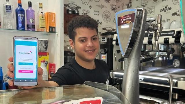 Un camarero muestra la aplicación de BuscoExtra desde su puesto de trabajo en un bar.
