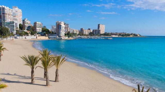 Una playa alicantina con apartamentos al fondo.