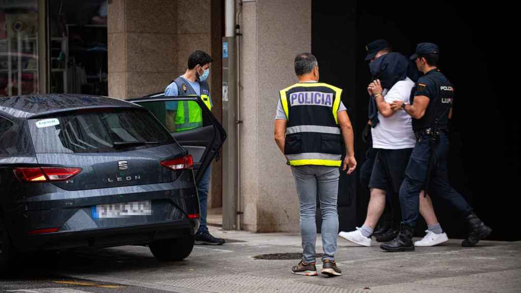Agentes de policía trasladan a un detenido durante un operativo policial en Sanxenxo.