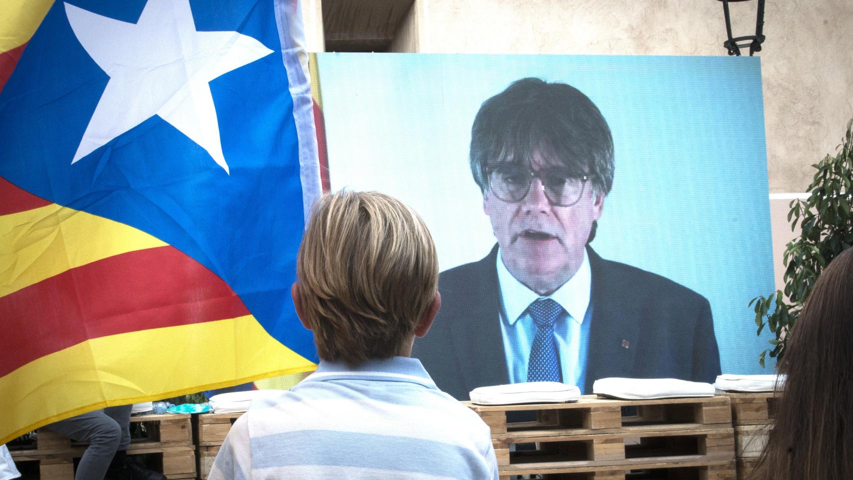 Un niño observa la intervención telemática de Puigdemont en el mitin central de JxCAT, a 16 de julio de 2023, en en Amer, Gerona.