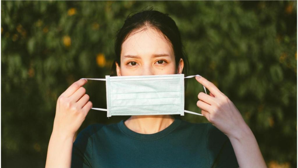 Una mujer se coloca una mascarilla